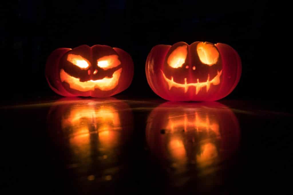 Two carved out pumpkins lit by candles for Halloween