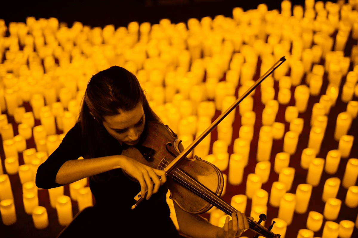A violinist performs by candlelight