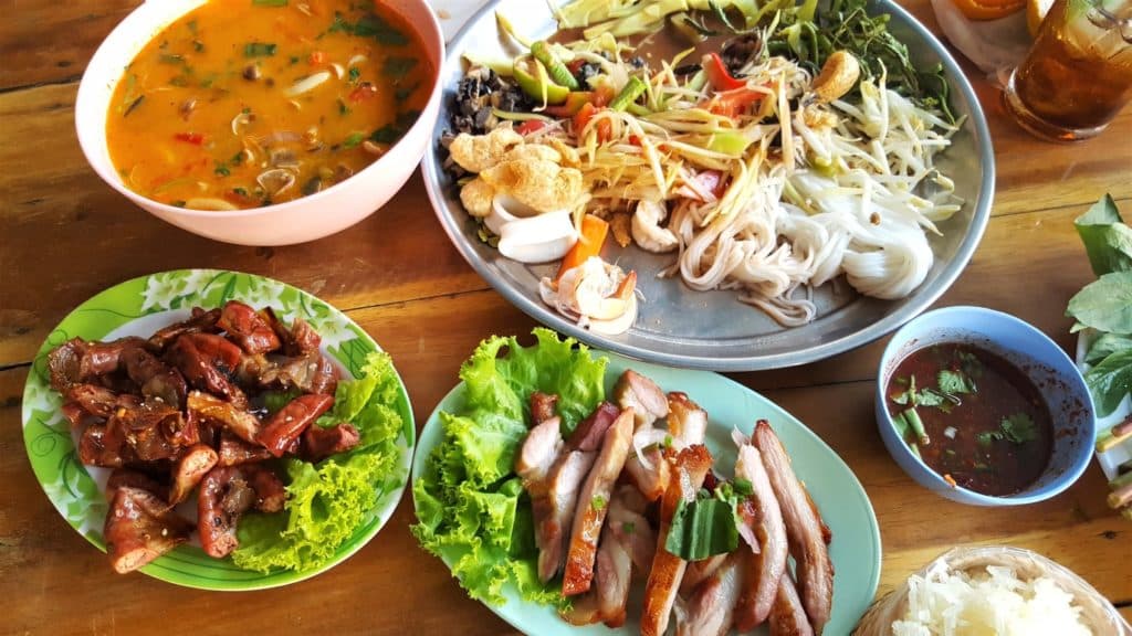 Several plates of Thai food including sliced pork at a Thai restaurant.